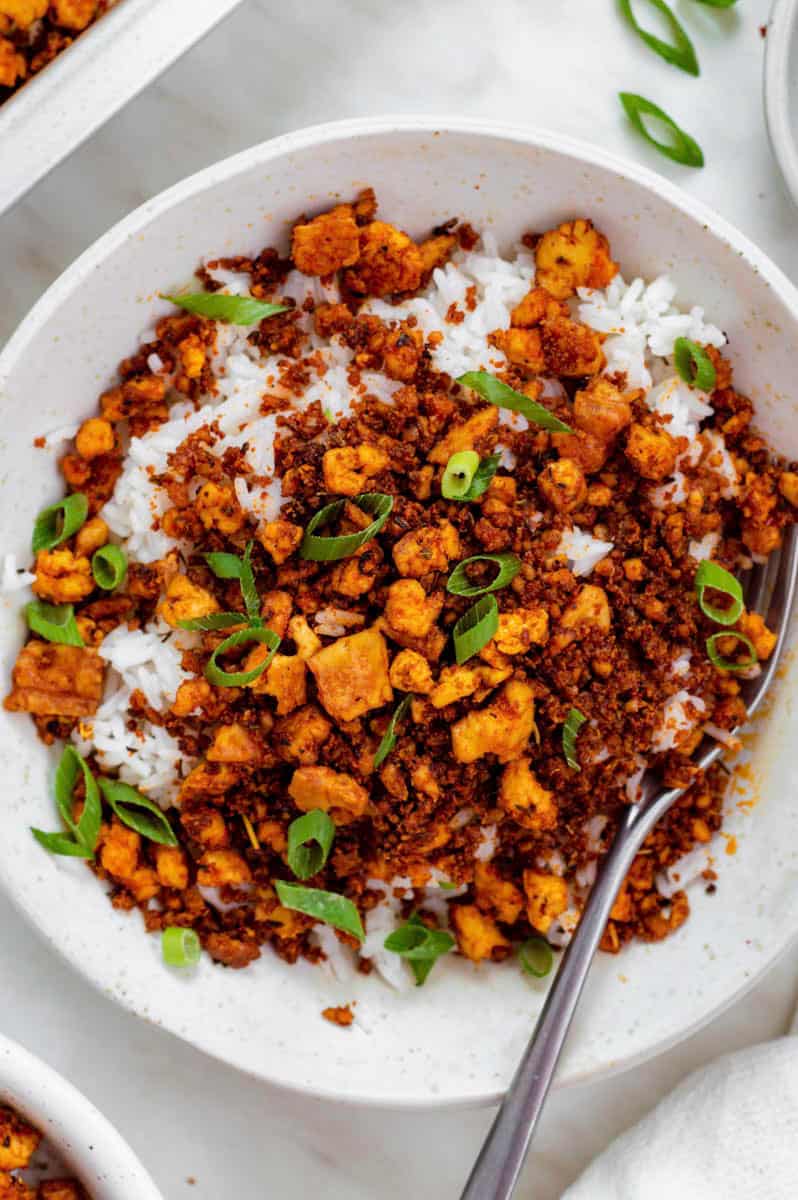 A close-up shot of tofu ground beef served over cooked rice in a white bowl.