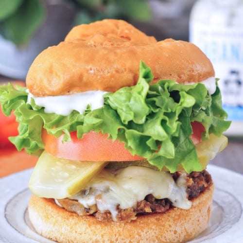 mushroom burger with toppings on a bun on a white plate.