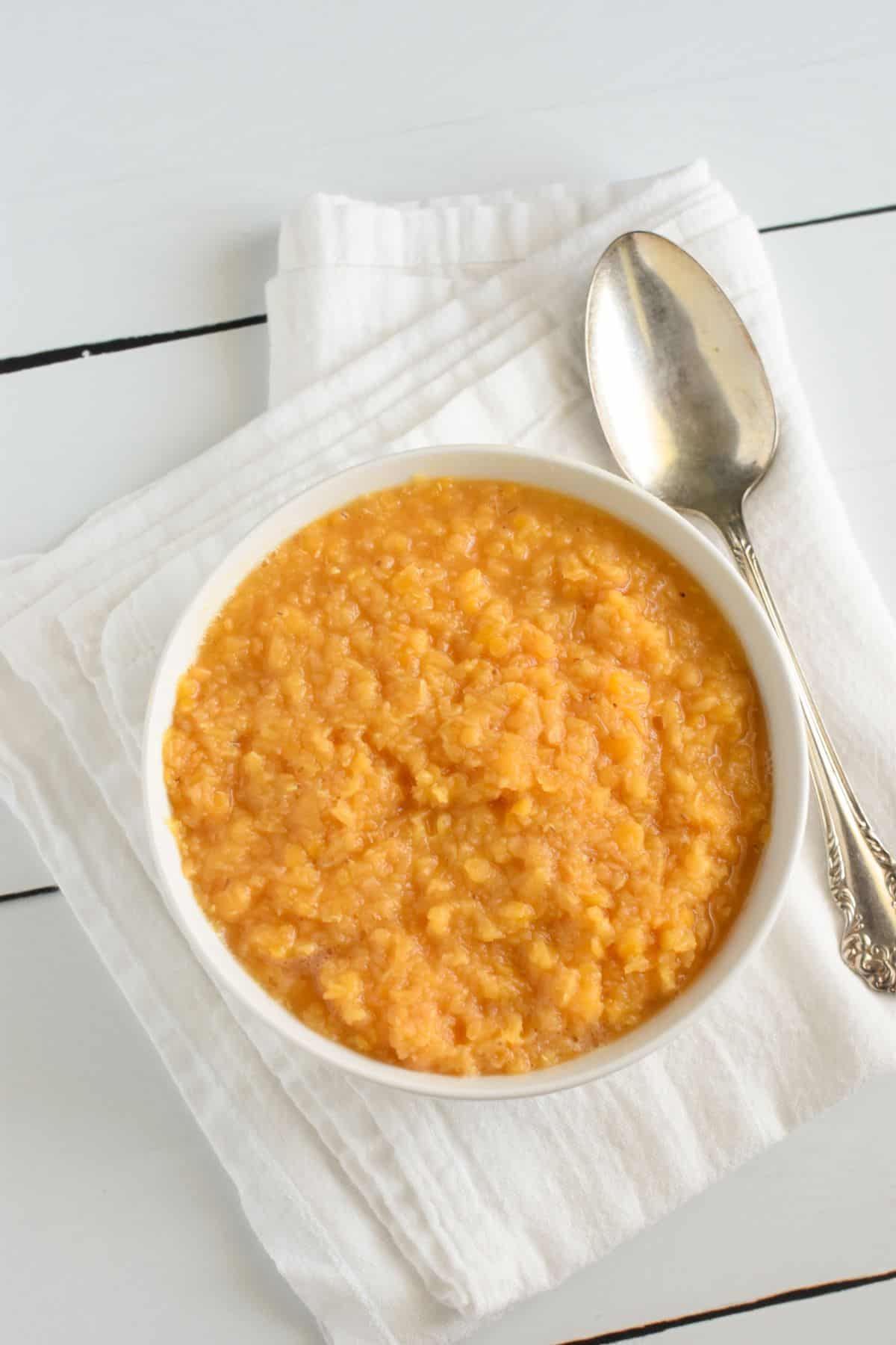 lentils after cooking in a white bowl with a spoon next to it.