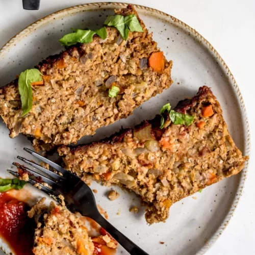 overhead of slices of chickpea loaf on a plate with a fork cutting into one.