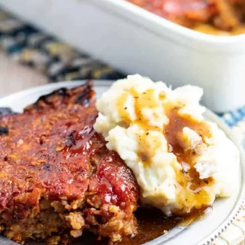 serving of vegan loaf on a plate with mashed potatoes and gravy.