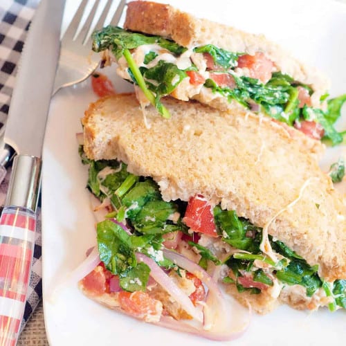 Vegetable sandwich on a plate with a fork and knife next to it.