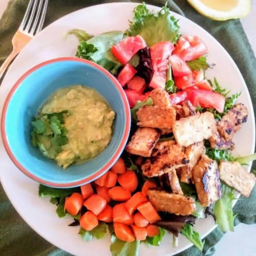 Salad in a bowl with chopped veggies and a dressing.