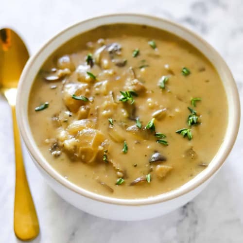 vegan mushroom soup in a bowl with a spoon to the left of it.