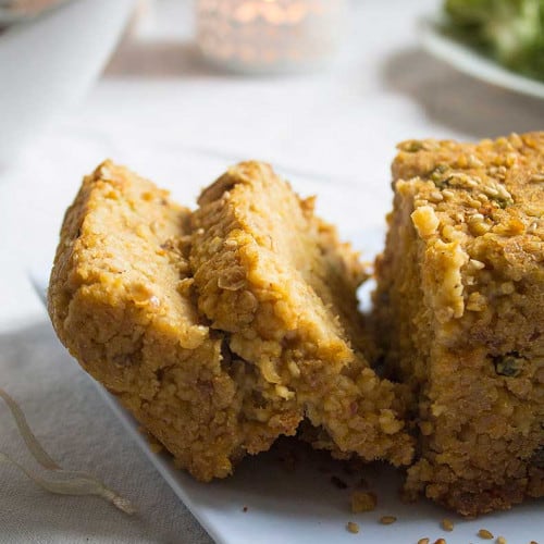 close up of two slices of holiday lentil loaf coming off of the whole loaf.