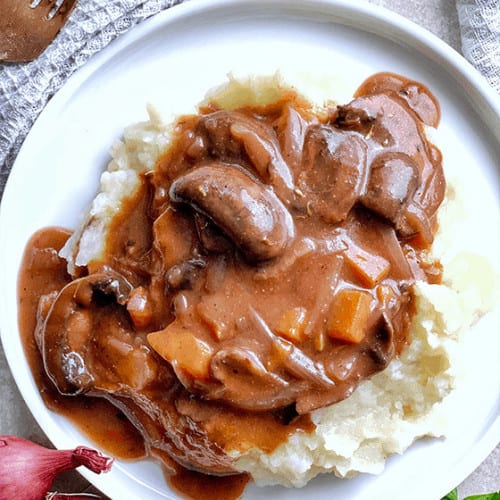 mushroom burgundy on top of mashed potatoes on a plate.