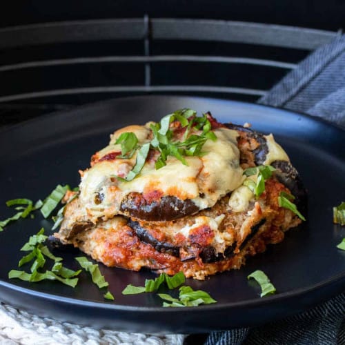 vegan eggplant Parmesan in a black dish with basil garnish.