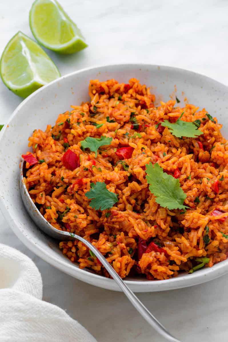 A white bowl filled with vegan Mexican rice topped with cilantro leaves.