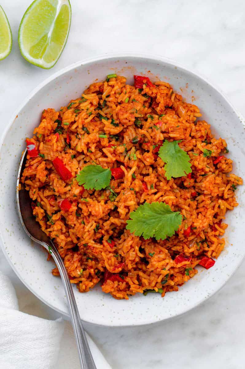 Vegan Mexican rice served in a white bowl and topped with cilantro. A silver spoon placed on the right side of the bowl.