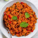 Vegan Mexican rice served in a white bowl and topped with cilantro. A silver spoon placed on the right side of the bowl.