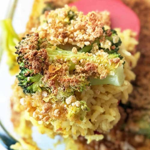 A spoonful of rice and broccoli casserole coming from the dish.