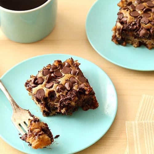 A blue plate with a chocolate chip banana dessert with a fork on the table.