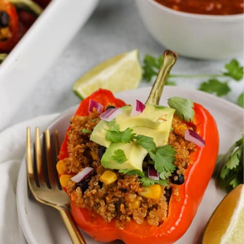 Stuffed bell pepper on a plate with a fork and lime wedge.