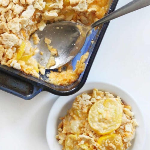 Dish of yellow squash casserole with a spoon and a serving on a plate.