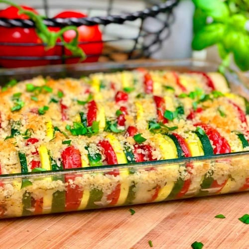 Long casserole dish with alternating zucchini, yellow squash and tomatoes with breadcrumb topping.