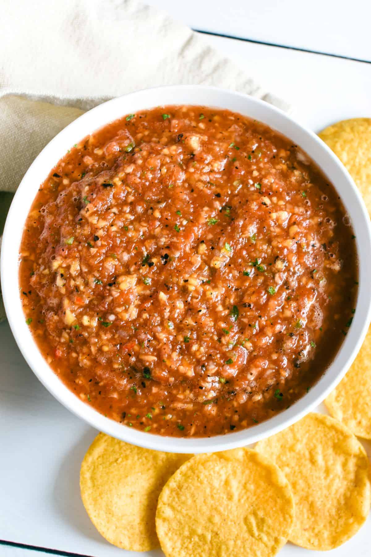 overhead of mango habanero salsa in a white bowl with chips around.