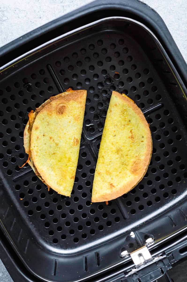 Two quesadillas in the air fryer basket.