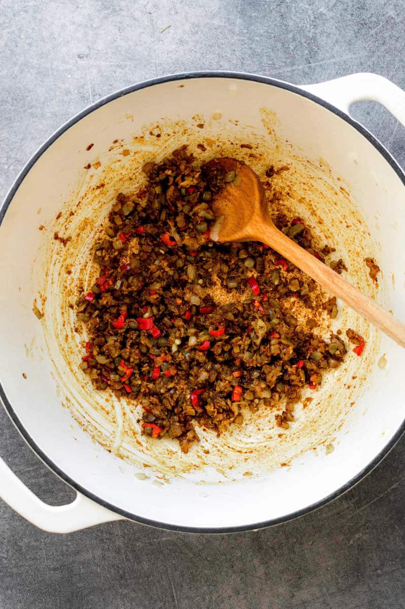 Sauteeing aromatics and spices in a white Dutch oven.