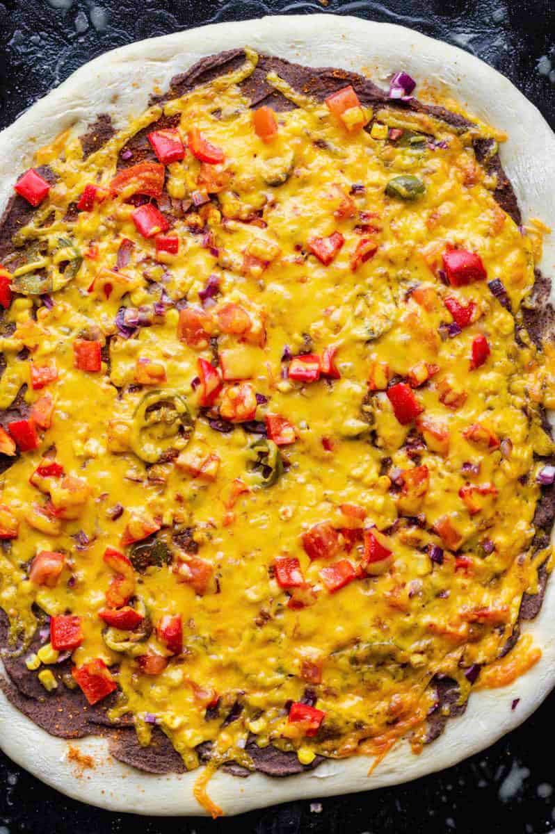 Baked vegetarian mexican pizza on a black baking sheet.