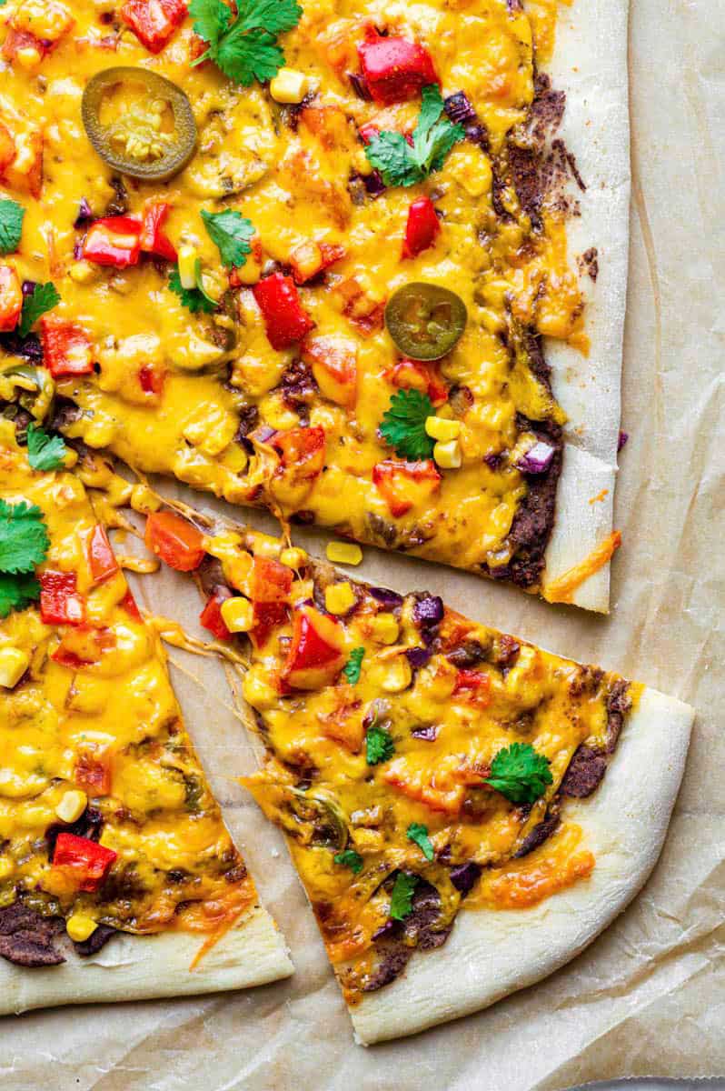 A piece of pizza on a brown parchment paper topped with fresh cilantro.