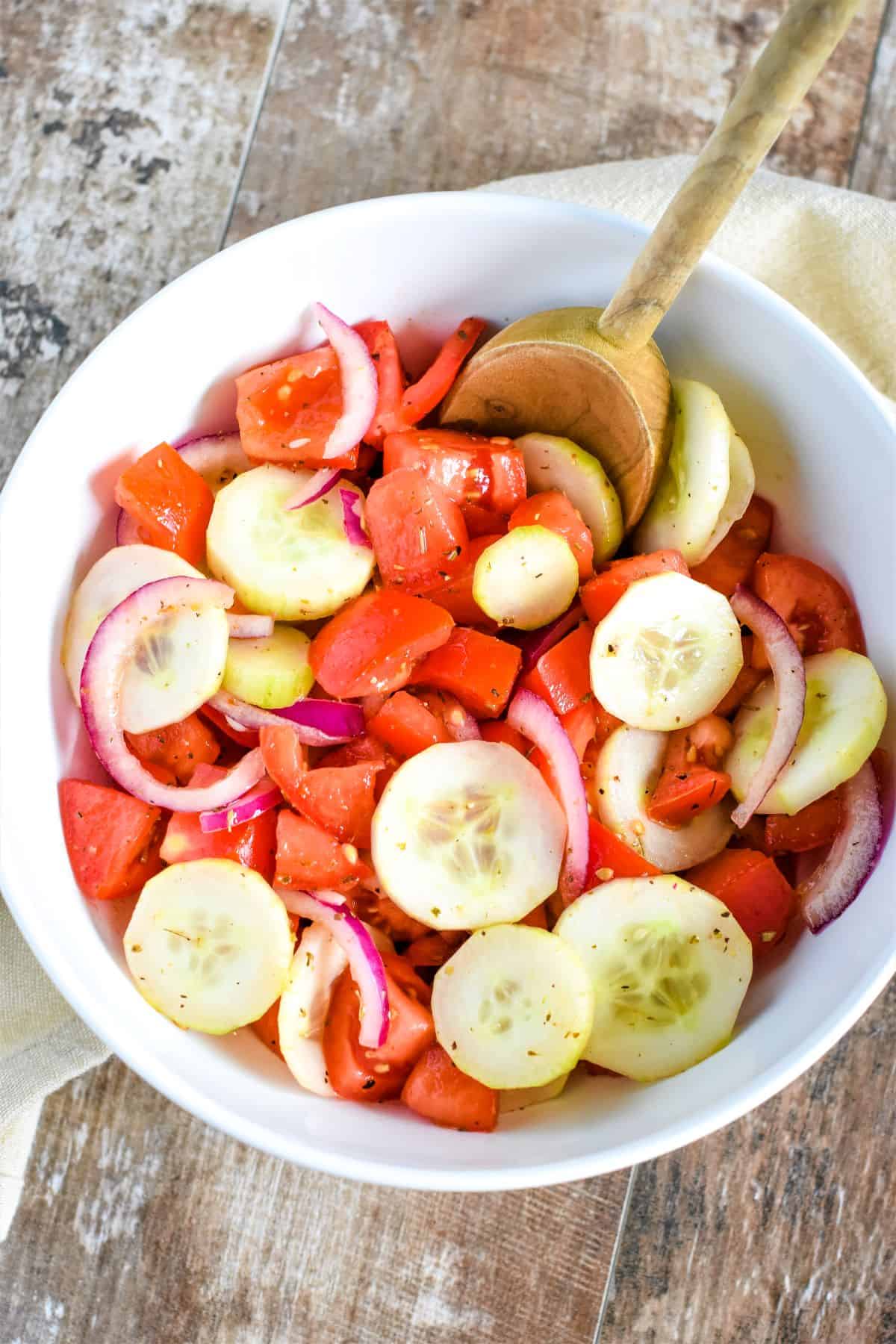 salad in a white bowl with a wooden spoon in it.