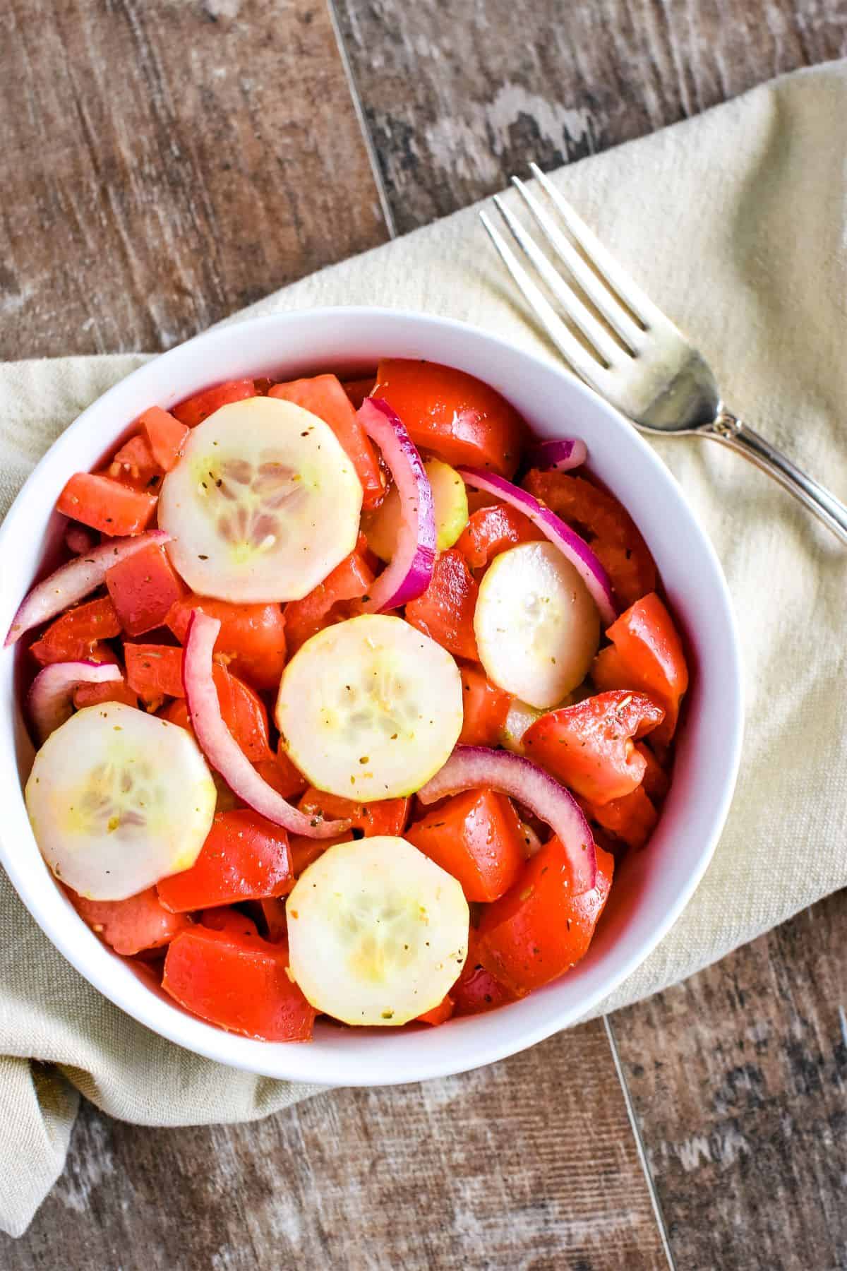 overhead of salad in a small white bowl with a fork next to it.