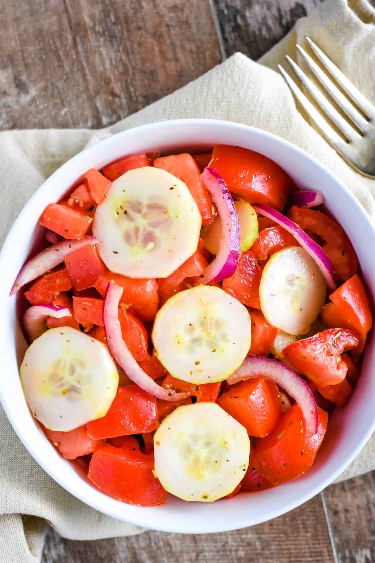 overhead of salad in white bowl with part of fork in view behind it.