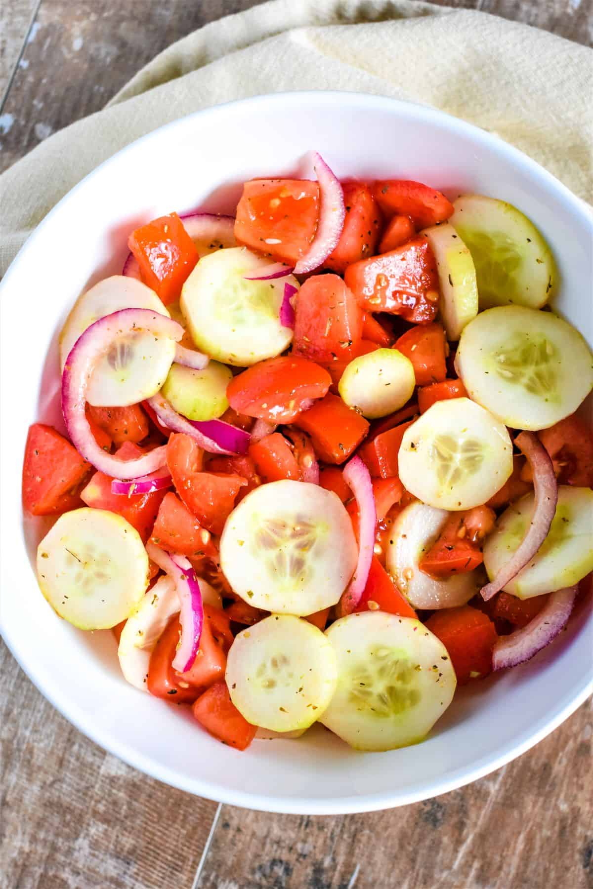 overhead of salad in a white bowl with kitchen napkin behind it.