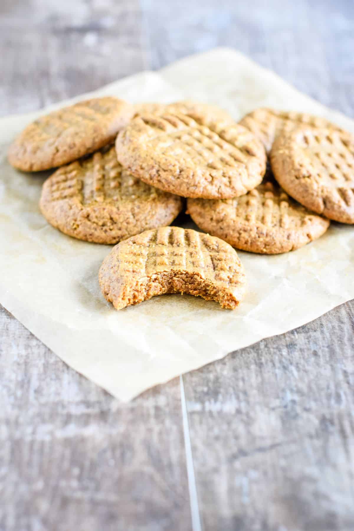 cookies on top of each other on parchment with one by itself in front with bite taken out.