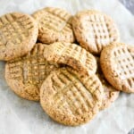 close-up of cookies on parchment with one on top bit into.