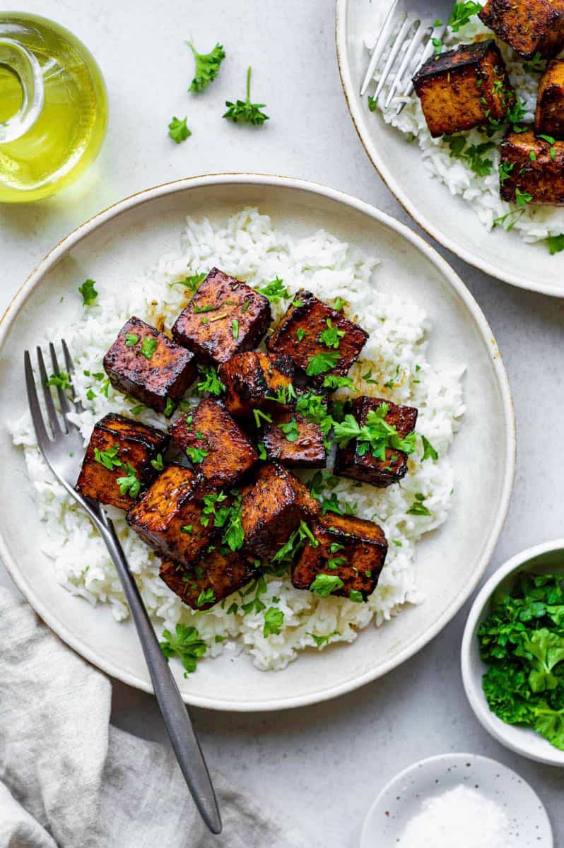 overhead of balsamic tofu in a white bowl on top of rice with a fork in it.