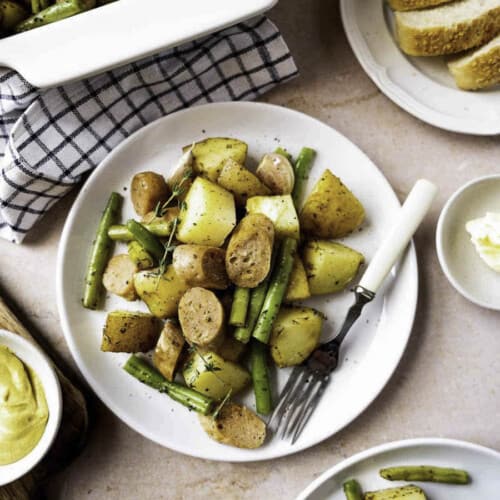 Green beans, potatoes and sausage on a white plate with a fork placed in it.