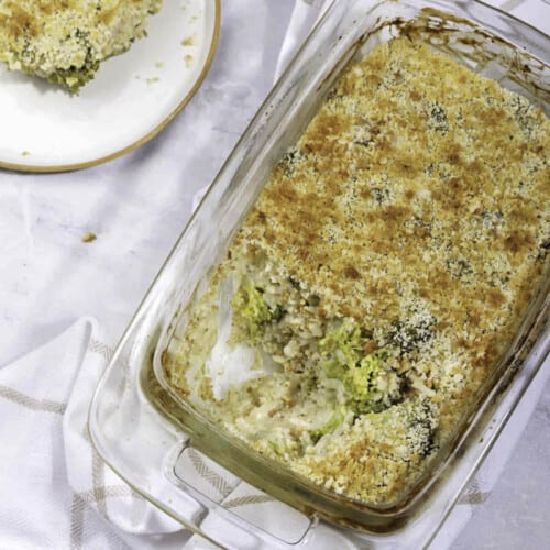 A top view of vegan broccoli casserole, with portion served on a plate beside the dish.