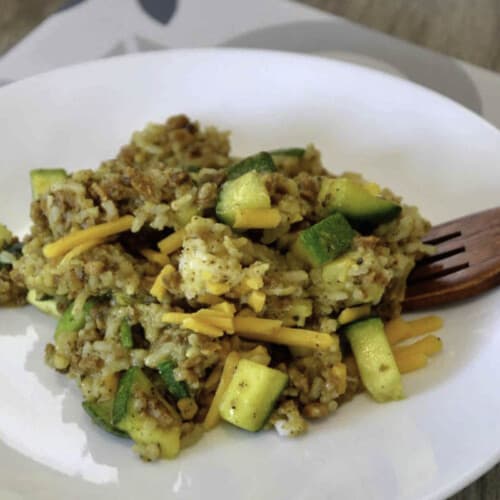 Vegan zucchini bake on white plate with wooden fork.