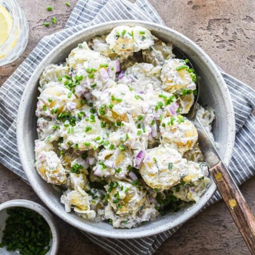 overhead of sour cream and onion potato salad in a bowl on a kitchen towel.