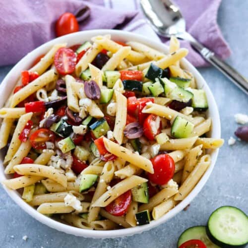 overhead of penne pasta salad in a white bowl.