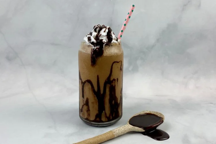 frappuccino in a glass with whipped cream and a straw.