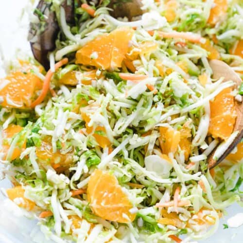 overhead of shaved brussels sprout salad in a bowl with a serving spoon in it.