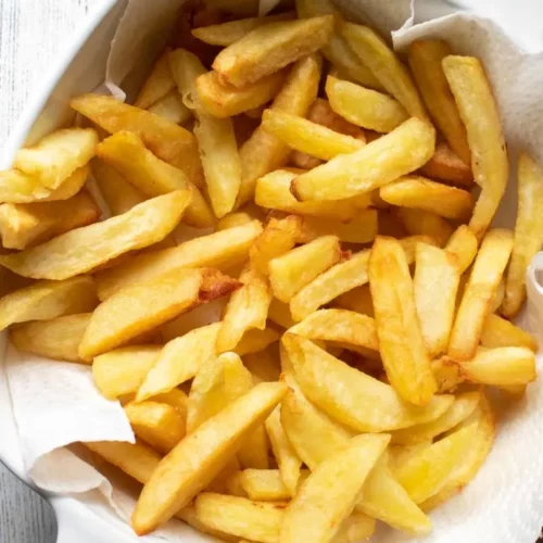 overhead of homemade fries on a napkin in a white casserole dish.