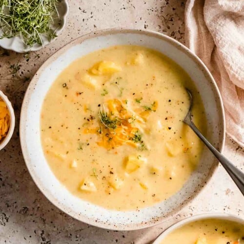 overhead of serving of vegetarian potato soup in a bowl with a spoon in it.