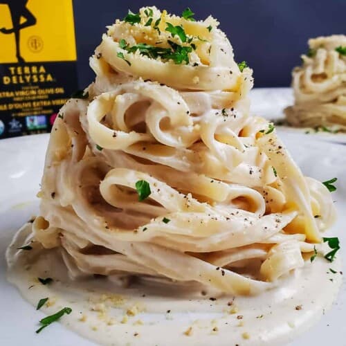 mountain of vegan fettuccine alfredo on a white plate.