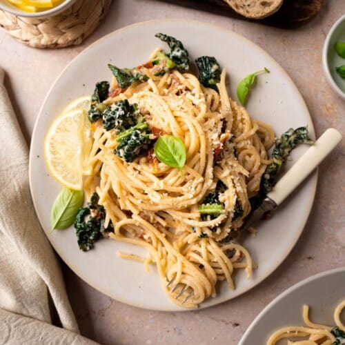 overhead of serving of cavolo nero pasta on a white plate with a fork twirling some of the pasta.