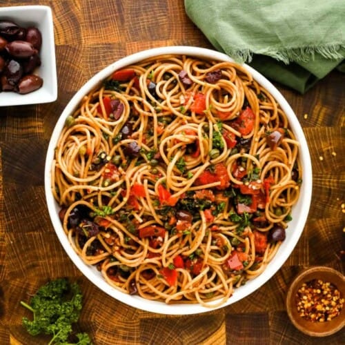 overhead of pasta puttanesca in a large white serving bowl.