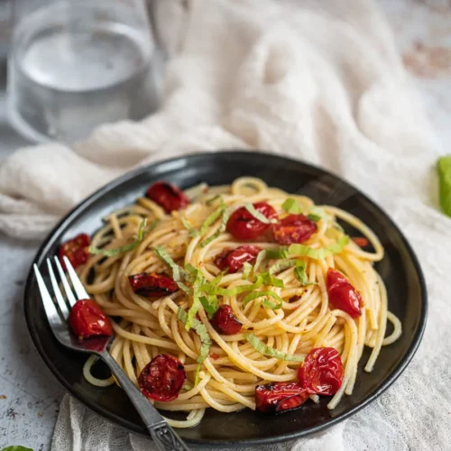 spaghetti aglio-olio-e-peperoncino on a black plate with a fork.