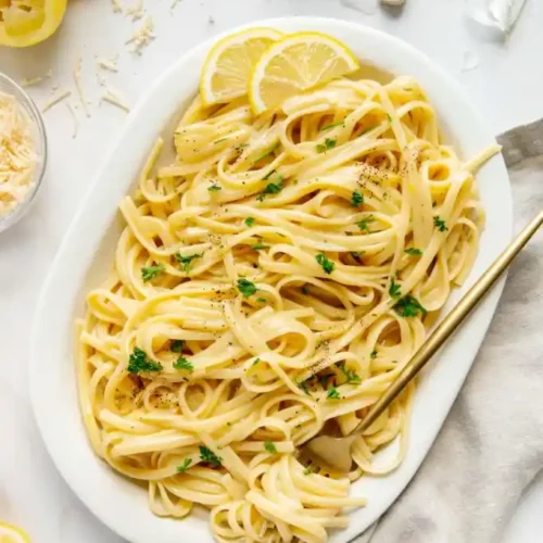 overhead of pasta al limone in a white serving dish with a big fork.