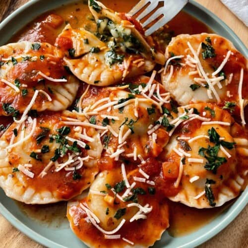 close-up of fork picking up a vegan ravioli from a plateful.