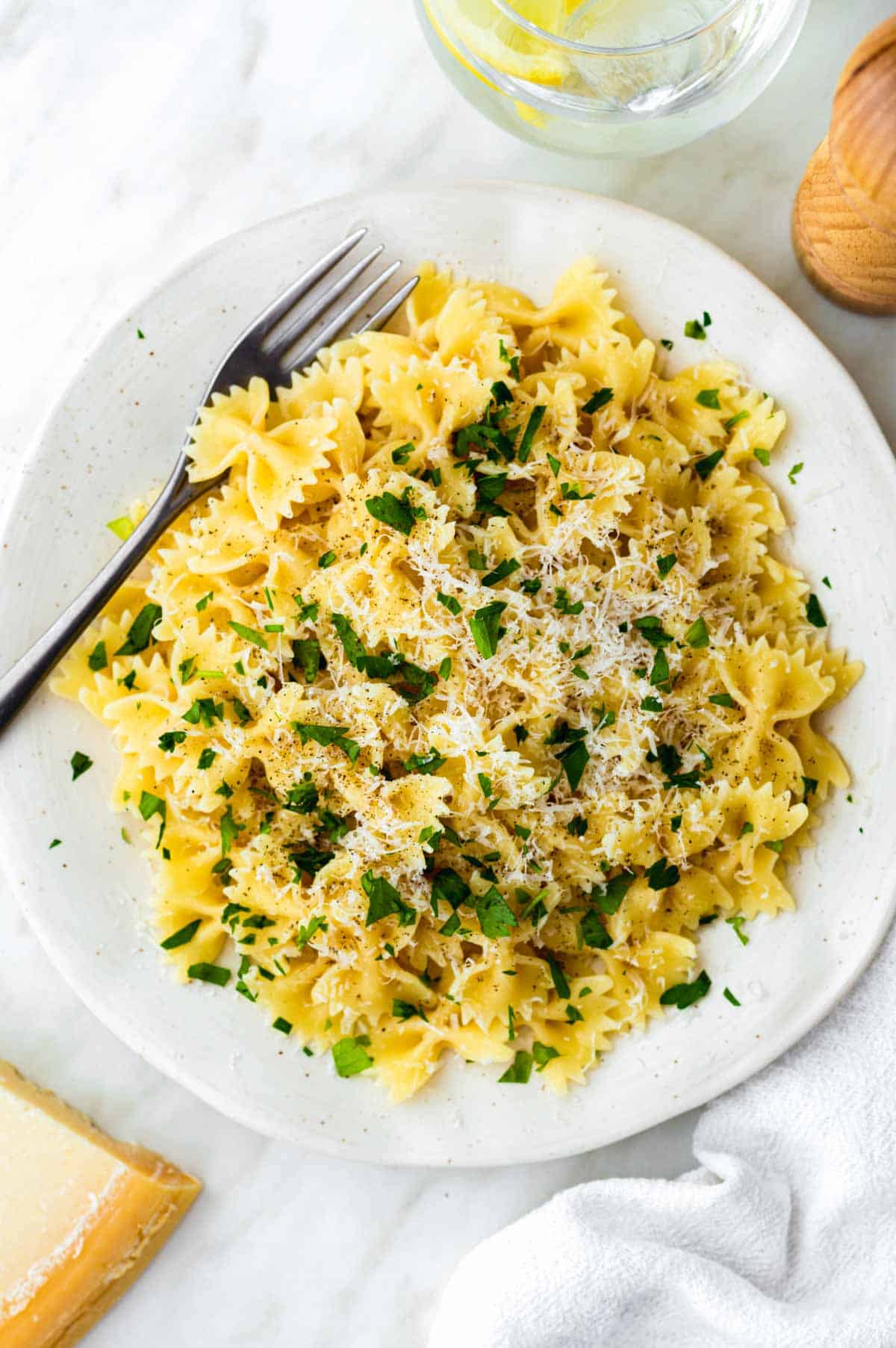 Microwave cooked pasta served on a white plate and topped with grated parmesan cheese and chopped parsley.