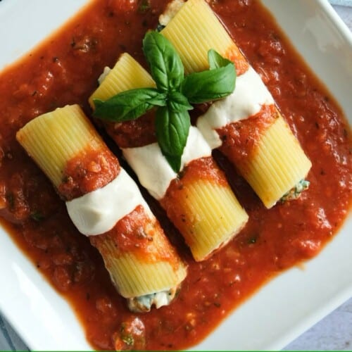 overhead of three vegan cannelloni on a white square dish with sauce.