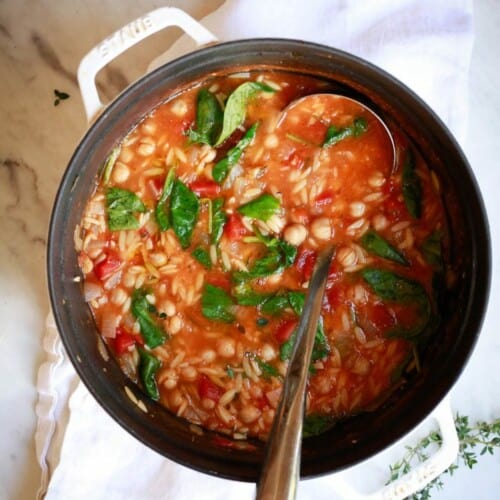 overhead of pasta e ceci in a large pot with a ladle.