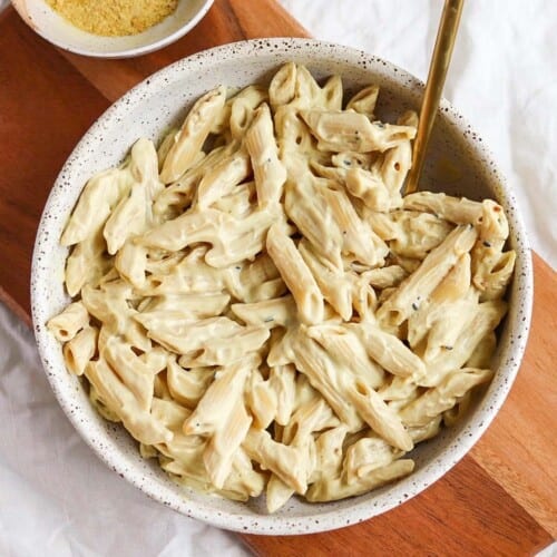 Vegan mac and cheese served in a white bowl with a fork in it.